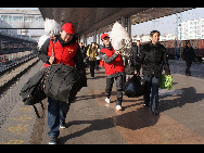 Two volunteers carry luggage for passengers at Hohhot railway station, capital city of north China's Inner Mongolia on January 30, 2010. [Xinhua]