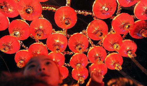 A kid takes a look at the red lanterns displayed at People's Park in Xining, capital of northwest China's Qinghai Province, February 1, 2010. Local residents were attracted by various lanterns displayed at the park in Xining. 