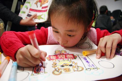 A little girl is engrossed in drawing cartoon painting of tiger in Nanjing, east China's Jiangsu Province, January 23, 2010.