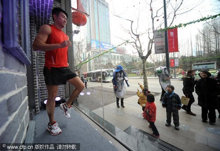 Passers-by watch a model jogging in the window of a sportswear shop in Shanghai Feb 1, 2010. The shop is going to invite professional models to perform throughout the Spring Festival holidays to promote a healthy workout, with themes such as World Expo 2010, the Spring Festival and Valentine's Day.