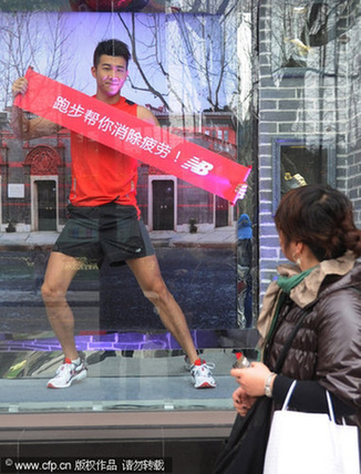 A passer-by watches a model jogging in a window of a sportswear shop in Shanghai on Feb 1, 2010. The banner in the model's hands reads: 'Jogging helps you get away from fatigue.'