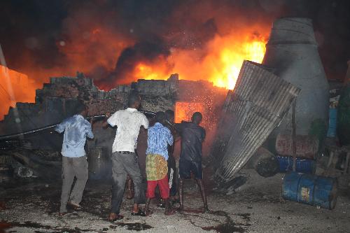 People try to extinguish the fire in Bakara Market, where fuel in barrels and tanks is sold, in Mogadishu, capital of Somalia, Feb. 2, 2010. The fire destroyed hundreds of thousands of dollars&apos; worth of goods, mainly petrol and diesel.[Ismail Warsameh/Xinhua]