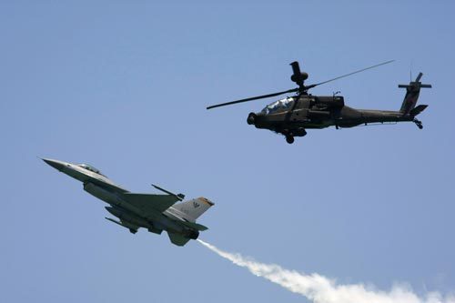 A Republic of Singapore Air Force (RSAF) AH-64 Apache attack helicopter and a RSAF F-16C Fighting Falcon fighter jet fly in formation during the Singapore Airshow February 2, 2010. 