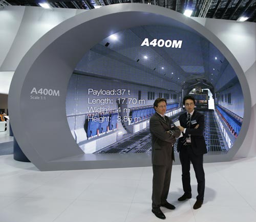 EADS staff stand near a life-size scale display of the interior of the Airbus A400M military transport plane, at the EADS display area at the Singapore Airshow February 2, 2010. The countries buying the Airbus A400M hope to reach a deal with aerospace and defence group EADS this week on how to cover the programme&apos;s soaring costs, France&apos;s defence minister said on Monday.[Xinhua] 