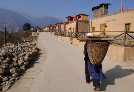 A Qiang nationality elderly woman walks by the newly built houses in Luobo village, Wenchuan county, southwest China’s Sichuan province, January 28, 2010. All the villagers have moved into their new houses before the Spring Festival. [Xinhua]