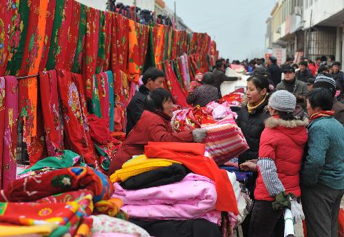 Local villagers in hustle and bustle throng to the rural bazaar of Spring Festival to select and buy new drapery, in Shanting Town, Zaozhuang, east China's Shandong Province, Feb. 2, 2010. The festival atmosphere of local rural fairs for the new Spring Festival is getting warming up, with the new Spring Festival of the year of tiger approaching. (Xinhua/Gao Qiming)