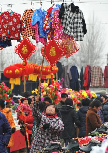Local villagers in hustle and bustle throng to the rural bazaar of Spring Festival to select and buy new clothings, in Shanting Town, Zaozhuang, east China's Shandong Province, Feb. 2, 2010. (Xinhua/Gao Qiming) 