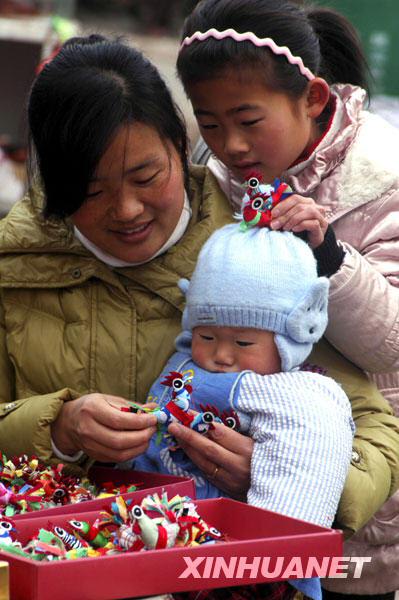 A mother chooses 'colorful chicks' for her children at fair of Matou Town, Shandong Province on February 3, 2010. According to the local custom, on Lichun (Beginning of Spring), children always wear colorful chicks on their hat for a lucky New Year and good health. 