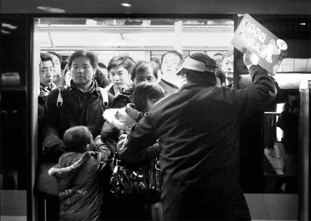 A volunteer surnamed Zhang, who is a local high school teacher, pushes passengers into a subway carriage in a Shanghai station Wednesday morning. [Gao Erqiang]