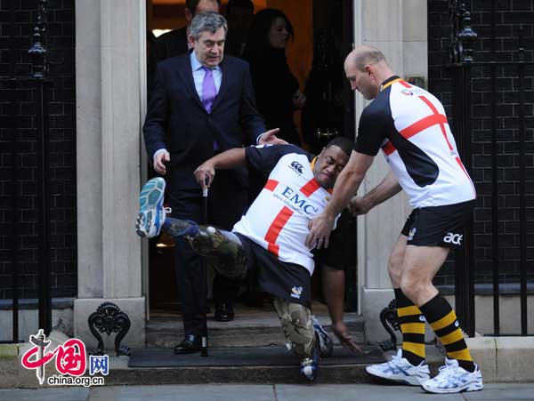 Prime Minister Gordon Brown and rugby player Lawrence Dellaglio (right) help Derek Derenalagi (centre) as he falls on the doorstep of 10 Downing Street, London. The former soldier who lost both legs in Afghanistan in 2007 was there to promote a St Georges Day rugby match to raise money for Help For Heroes. [CFP]