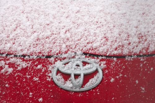 The Toyota logo is seen on a car covered with snow at a retailer in Vienna February 4, 2010. Toyota Motor Corp shares slid to a 10-month low on Thursday after the U.S. President Barack Obama administration stepped up the pressure on the world's largest carmaker to address a range of safety issues.