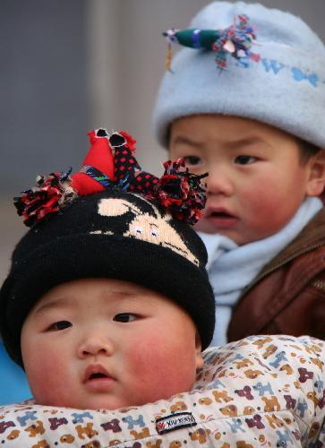 Children wearing hats decorated with cloth dolls of Spring Cock are seen at Xinli Village of Tancheng County, east China's Shandong Province, February 4, 2010, the day of Spring Begins. 