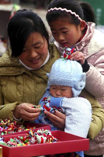 A mother buys cloth doll of Spring Cock for her child in Matou Township of Tancheng County, east China's Shandong Province, February 3, 2010, one day ahead of Spring Begins. [Xinhua photo]