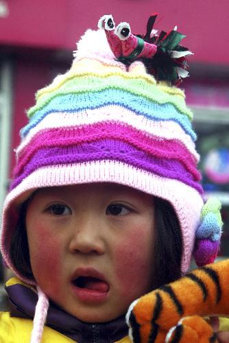 A girl wearing a hat decorated with cloth dolls of Spring Cock is seen in Matou Township of Tancheng County, east China's Shandong Province, February 3, 2010, one day ahead of Spring Begins. [Xinhua photo]