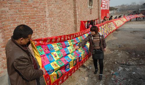 Villager Wang Jinping (C) shows her 30-meter-long embroidery work at Sanjiazhuang Village of Guowang Township in Fengxiang County, northwest China's Shaanxi Province, February 4, 2010.