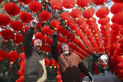 Two people enjoy the sightseeing of the long corridor decorated with full range of florid red lanterns inside the Ditan (Altar of the Earth) Park, as the festival atmosphere for the 25th Spring Festival Temple Fair, slated from February 13 to 20, at Ditan Park is drumming up, in Beijing, February 4, 2010. 