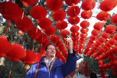 A foreigner takes handy phone snapshot inside the long corridor decorated with full range of florid red lanterns in the Ditan (Altar of the Earth) Park, as the festival atmosphere for the 25th Spring Festival Temple Fair, slated from February 13 to 20, at Ditan Park is drumming up, in Beijing, February 4, 2010.