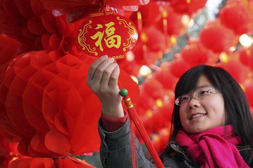 A girl fondles an auspicious knot with Chinese Character of felicity inside the long corridor decorated with full range of florid red lanterns in the Ditan (Altar of the Earth) Park, as the festival atmosphere for the 25th Spring Festival Temple Fair slated from February 13 to 20, at Ditan Park is drumming up, in Beijing, February 4, 2010.