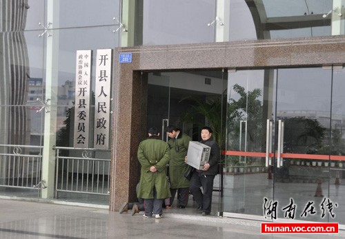 Liao Fuping and Zhu Daguo stand at the entrance to the Kaixian county office building as Yin Xianqiong lies at their feet in this Jan 13 photo taken and posted online by an unnamed netizen. 
