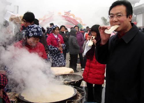 Tourists taste freshly baked pancakes during a pancake-baking exhibition contest in Yinan County, east China's Shandong Province, Feb. 7, 2010. (Xinhua