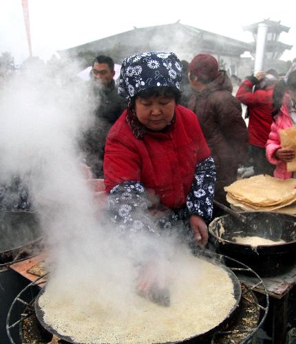 A housewife bakes pancakes during an exhibition contest in Yinan County, east China's Shandong Province, Feb. 7, 2010. (Xinhua/Du Yubao)