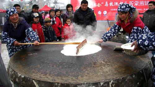 Housewives bake pancakes on a giant griddle during an exhibition contest in Yinan County, east China's Shandong Province, Feb. 7, 2010. (Xinhua 