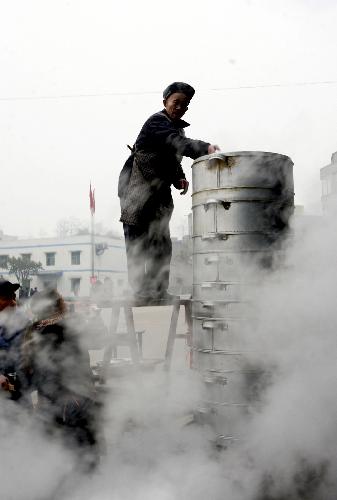 A cook makes steamed food for a group dinner for Xiaonian, the festival that falls on the 23rd or 24th day of the 12th month of the Chinese traditional lunar calendar, in a local company in Guang'an, southwest China's Sichuan Province, Feb. 6, 2010. A local company gave a banquet to its nearly 1,000 migrant workers in the honor of Xiaonian. (Xinhua/