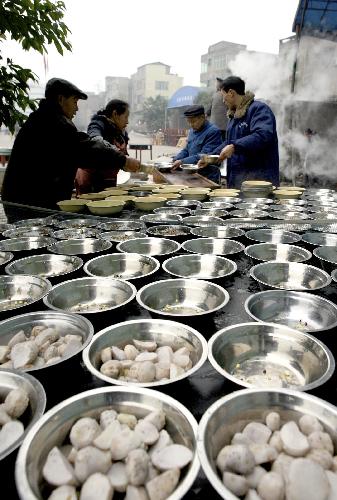 Cooks prepare for a group dinner for Xiaonian, the festival that falls on the 23rd or 24th day of the 12th month of the Chinese traditional lunar calendar, in a local company in Guang'an, southwest China's Sichuan Province, Feb. 6, 2010. A local company gave a banquet to its nearly 1,000 migrant workers in the honor of Xiaonian. (Xinhua/Qiu Haiying)