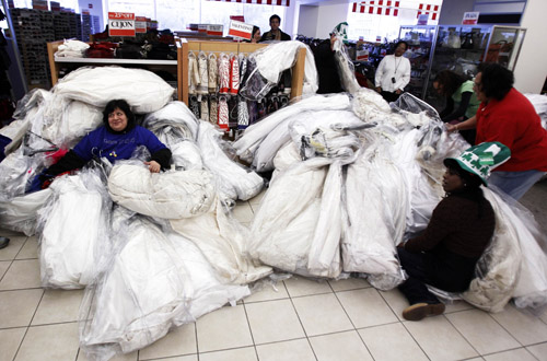 Shoppers guard their stashes of wedding dresses at Filene&apos;s Basement during a &apos;Running of the Brides&apos; bridal dress sale in New York February 5, 2010. [Xinhua/Reuters]