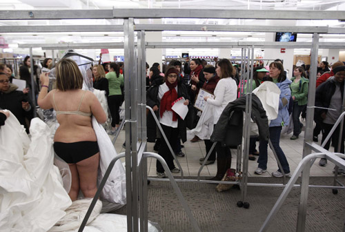 A shopper tries on a wedding dress at Filene&apos;s Basement during a &apos;Running of the Brides&apos; bridal dress sale in New York February 5, 2010. [Xinhua/Reuters]