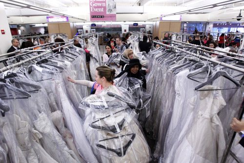 Shoppers fill their arms with wedding dresses at Filene&apos;s Basement during a &apos;Running of the Brides&apos; bridal dress sale in New York February 5, 2010. [Xinhua/Reuters]