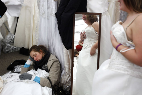 Dawn Schreiber falls asleep as the bride she is helping to look for dresses looks in a mirror inside Filene&apos;s Basement during a &apos;Running of the Brides&apos; bridal dress sale in New York February 5, 2010. [Xinhua/Reuters] 