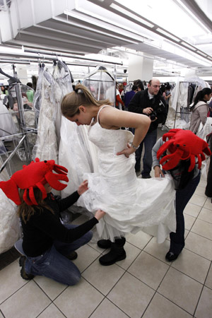 Shopper Erika Tobon is helped into a wedding dress at Filene&apos;s Basement during a &apos;Running of the Brides&apos; bridal dress sale in New York February 5, 2010. [Xinhua/Reuters]