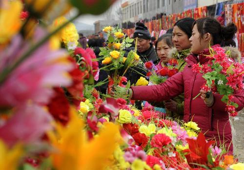 Women buy plastic flowers at a rural fair in Zaozhuang City, east China's Shandong Province, February 6, 2010. Festive fairs and markets are booming everywhere as people shop for the upcoming Chinese Lunar New Year that falls on February 14, 2010. [Xinhua photo]