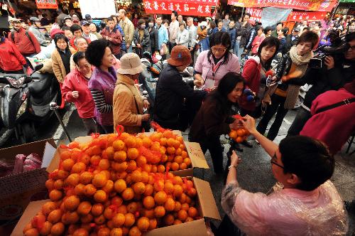 People line up to buy bargain fruits at a market in Taipei, southeast China's island province of Taiwan, Feb. 7, 2010.(