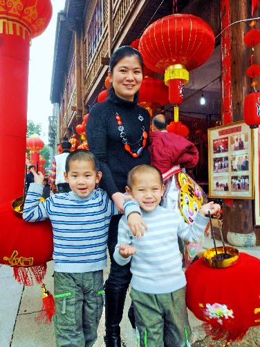 A pair of twins hold red lanterns with their mother at a New Year shopping mall in Fuzhou, capital of southeast China's Fujian Province, Feb. 8, 2010. Chinese people are preparing to celebrate the traditional Chinese New Year, or the Spring Festival, which falls on Feb. 14 this year. (Xinhua/