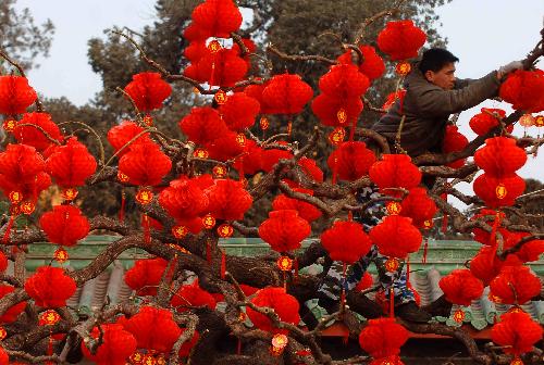 A staff member hangs red lanterns outside the entrance of Ditan Park in Beijing, China, Feb. 9, 2010. Red lanterns are seen in many parks in Beijing as the traditional Chinese new year approaches. (Xinhua