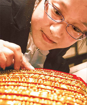A store clerk changes the price tags on gold jewelry in a department store in Shenyang, Liaoning province. Despite falling bullion prices, consumers in China are unlikely to buy more. [China Daily]