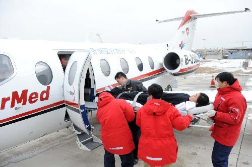 The medical workers of a medical flight service company board a 'patient' onto the jet during a drilling at Tianjin Binhai International Airport, north China's Tianjin Municipality, Feb. 9, 2010. A type of air ambulance service has come into operation recently in Tianjin and provides professional flight transport and nursing services to critical patients with respirators, monitors, stretchers, lox bottles etc. equipped on the jet. (Xinhua