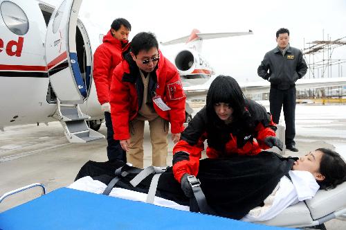 The medical workers of a medical flight service company put a 'patient' on the special stretcher during a drilling at Tianjin Binhai International Airport, north China's Tianjin Municipality, Feb. 9, 2010. (Xinhua