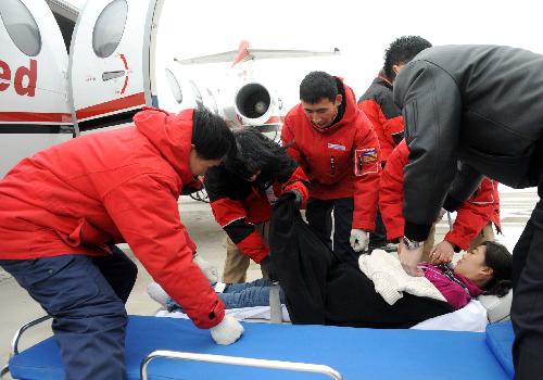 The medical workers of a medical flight service company lay a 'patient' onto the stretcher during a drilling at Tianjin Binhai International Airport, north China's Tianjin Municipality, Feb. 9, 2010. (Xinhua