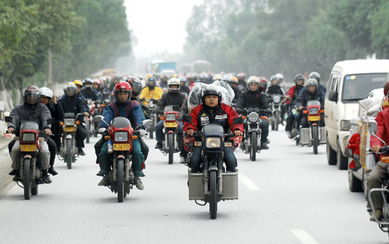 The photo taken on Monday, February 8, 2010, shows that migrant workers in Pearl River Delta Economic Zone of south China's Guangdong province are on their way home by motorcycle for Chinese New Year. [CFP]