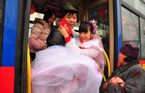 Groom Deng Hui takes his bride off a bus they chose as their wedding limousine in Sanhe Town of Fuyang City, east China&apos;s Anhui Province, on Feb. 9, 2010. [Xinhua]