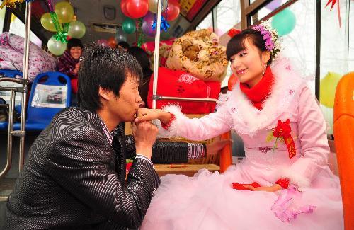 Groom Deng Hui kisses his bride&apos;s hand at a bus they chose as their wedding limousine in Sanhe Town of Fuyang City, east China&apos;s Anhui Province, on Feb. 9, 2010. [Xinhua]