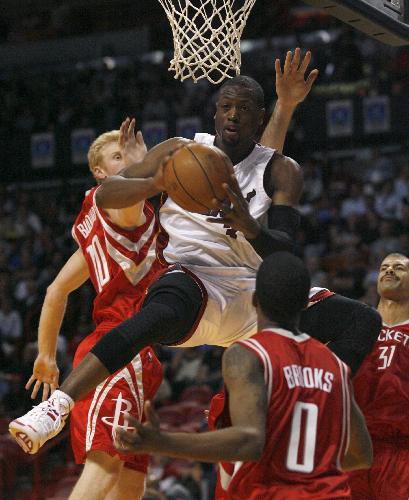 Miami Heat's Dwyane Wade (top) passes beneath the basket in the first half of their NBA basketball game against the Houston Rockets in Miami, Florida February 9, 2010.(Xinhua/Reuters Photo)