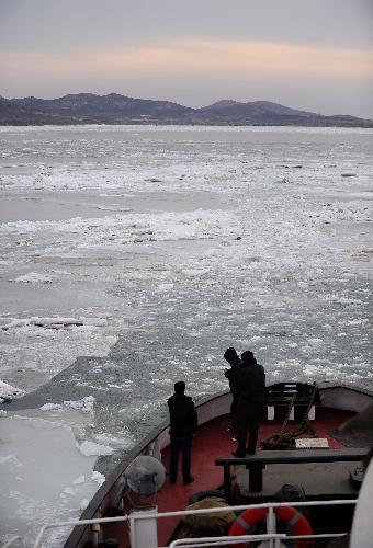 Three crew members observe sea ice on an icebreaker on its way to the Juhua Island in Northeast China's Liaoning province, on Feb 10, 2010. [Xinhua]