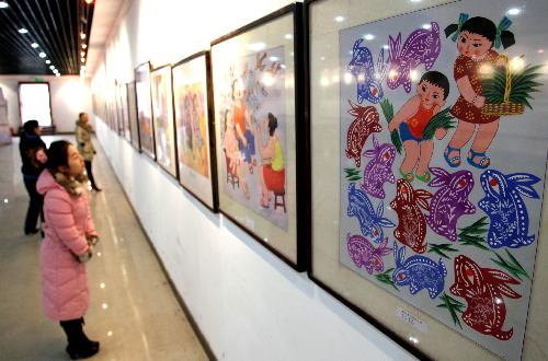Visitors view pictures displayed on an exhibition of farmers' paintings held in Xuchang City of central China's Henan Province, Feb. 10, 2010. A big number of pictures painted with simple and magnificent styles by local farmers of central China were showed on the exhibition to greet the coming Spring Festival. 