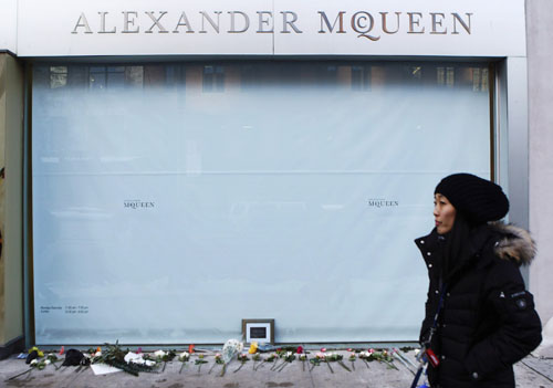 A woman walks by the Alexander McQueen store where a makeshift memorial lies outside, in New York February 11, 2010.