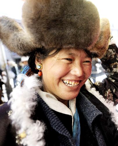 A woman chooses traditional hat at a market in Lhasa, capital of southwest China's Tibet Autonomous Region, Feb. 11, 2010, during the preparation for the Spring Festival and Tibetan Losar. 