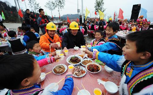 People raise cups for blessing during a banquet at a permanent settlement in Qionglai, city of southwest China's Sichuan Province, Feb. 11, 2010. 